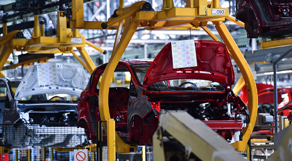 A car is being assembled on a production line, with workers and machinery actively engaged in the process.